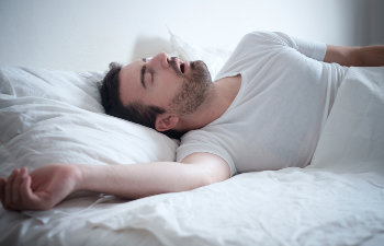 man in white pajamas sleeping and snoring